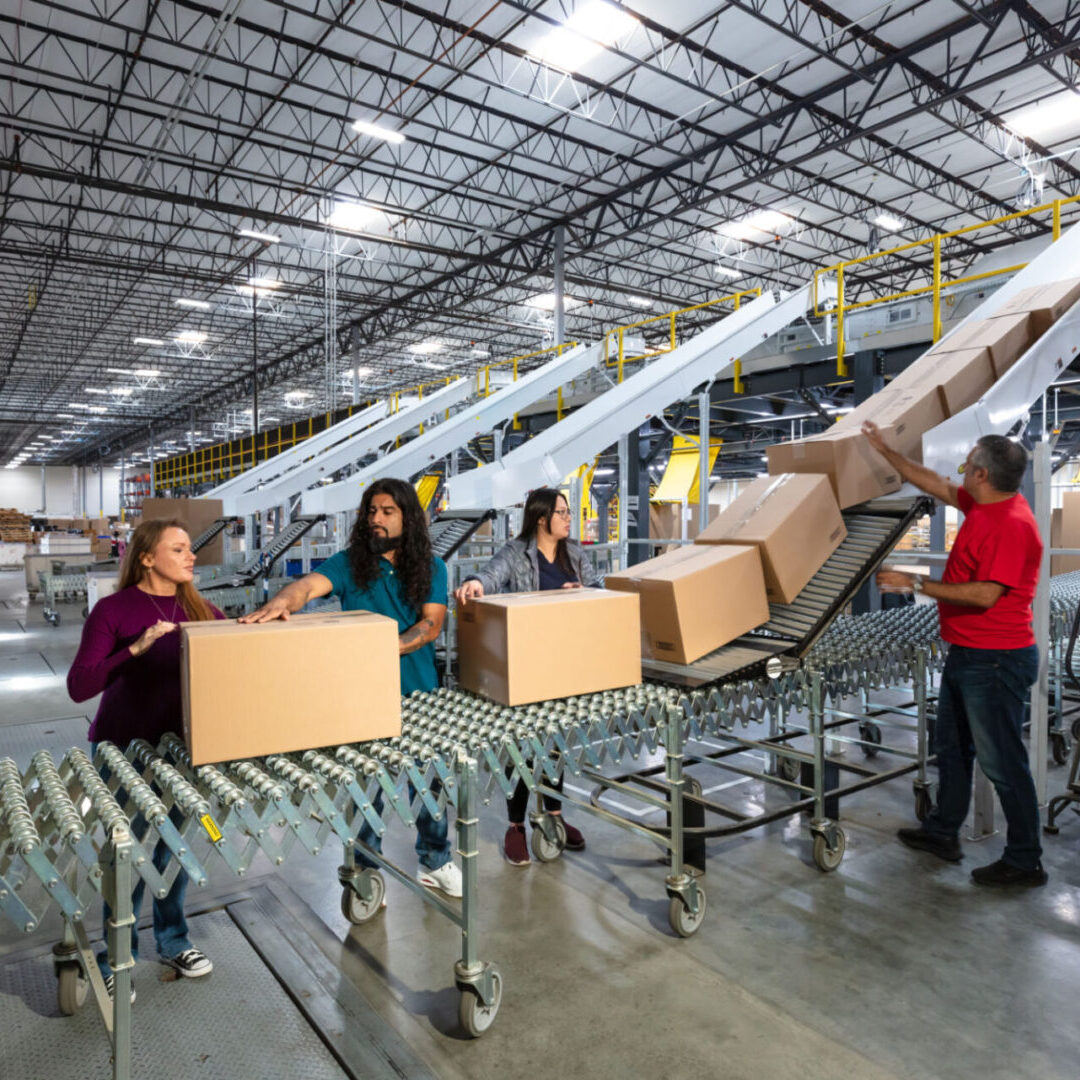 Workers sorting boxes in a large warehouse.